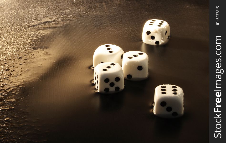 Close-up of five white dice lying on dark water background. Close-up of five white dice lying on dark water background