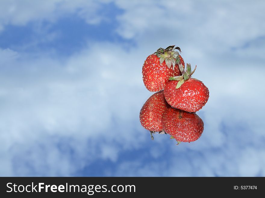 Two nice red strawberry with reverberation lying on blue sky background. Two nice red strawberry with reverberation lying on blue sky background