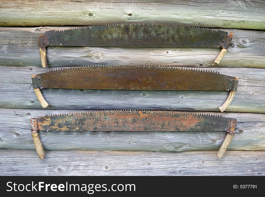 Old two-handled saws over a wooden background