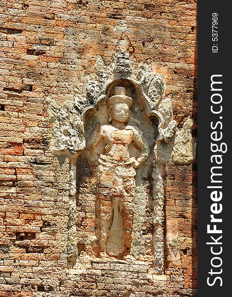 In Cambodia in the ancient city of Roulos the Hindu temple of Bakong was built in the 9th century by the king Indravarman I. View of a carved wall with a khmer guardian. In Cambodia in the ancient city of Roulos the Hindu temple of Bakong was built in the 9th century by the king Indravarman I. View of a carved wall with a khmer guardian