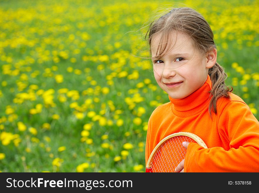 The little girl in orange clothes holds a tennis racket. The little girl in orange clothes holds a tennis racket