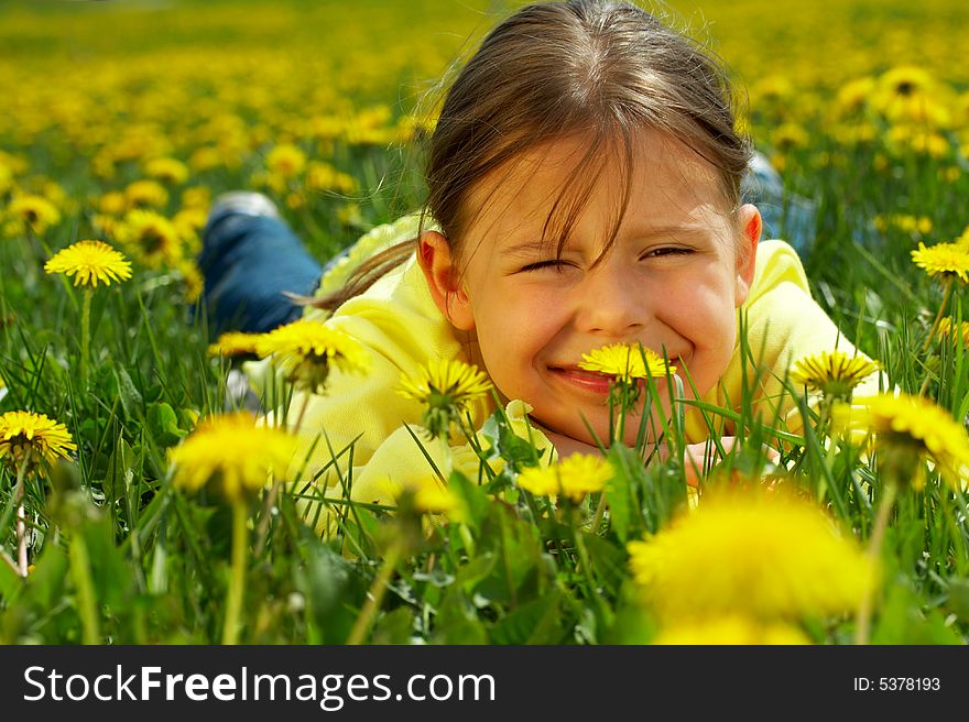 The little girl lays on a lawn among yellow flowers. The little girl lays on a lawn among yellow flowers