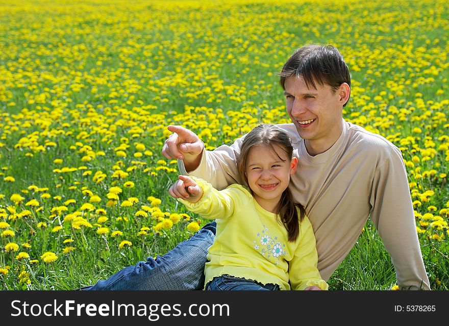 The father with a daughter sit on a lawn and show in a distance. The father with a daughter sit on a lawn and show in a distance