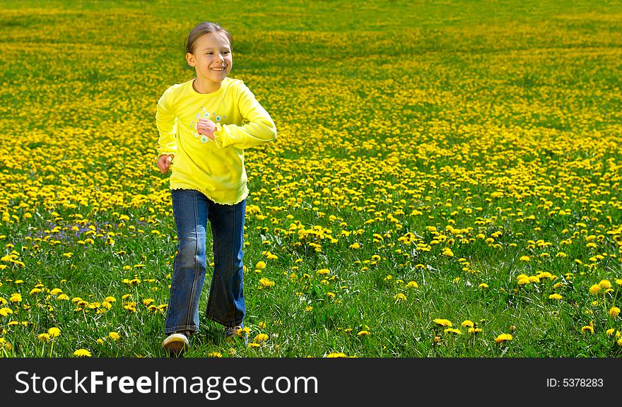 The girl runs on a green grass with dandelions. The girl runs on a green grass with dandelions