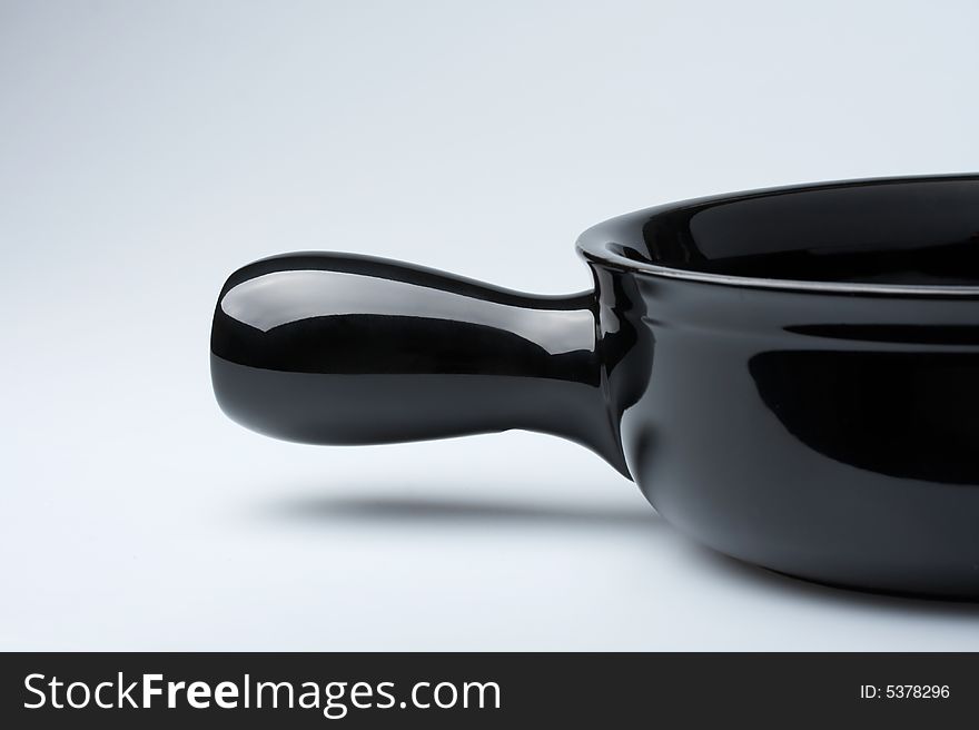 Part of a black saucepan on a white background. Part of a black saucepan on a white background