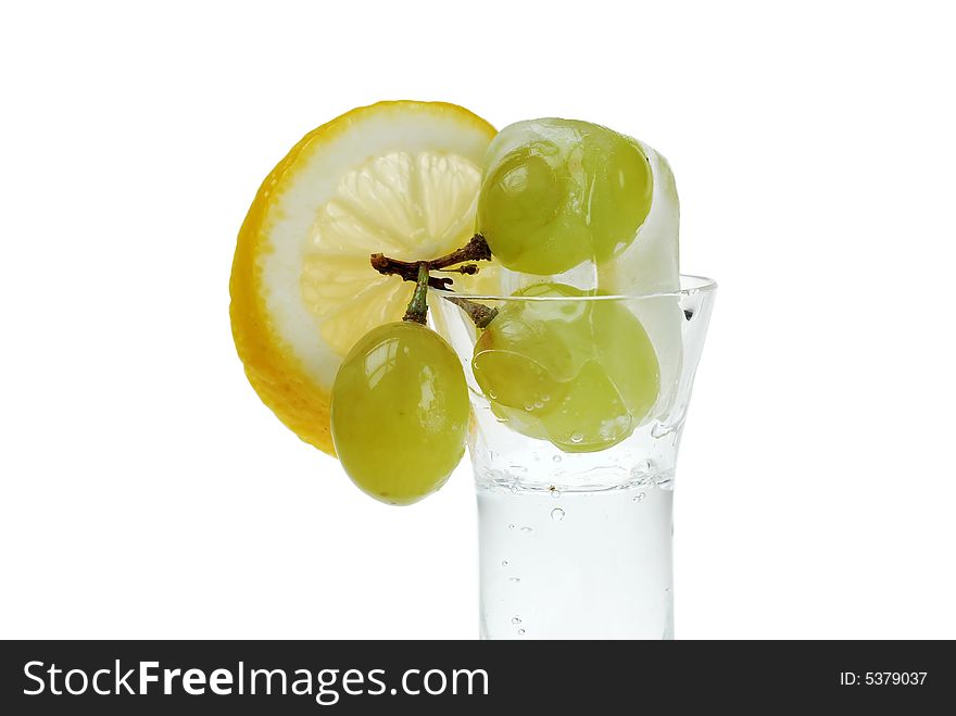 Close up to frozen grapes in shot glass filled with soda serving with fresh cut lemon slice. Close up to frozen grapes in shot glass filled with soda serving with fresh cut lemon slice
