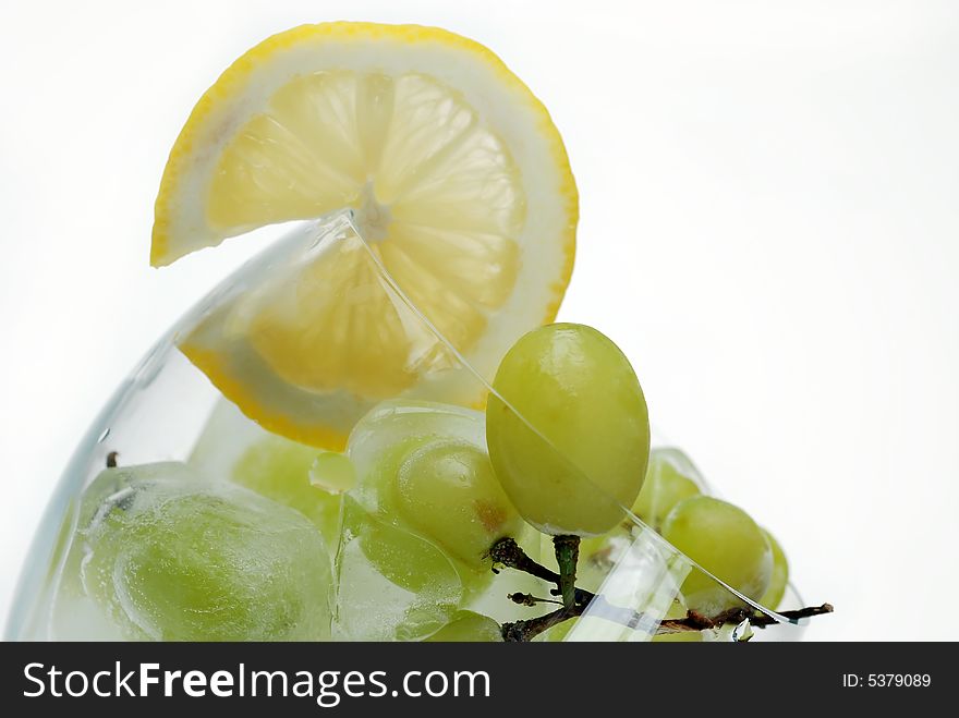 Close up to frozen grapes in wine glass filled with soda serving with fresh cut lemon slice. Close up to frozen grapes in wine glass filled with soda serving with fresh cut lemon slice