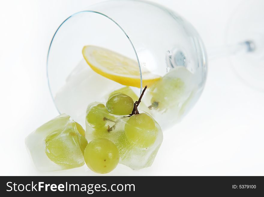 Close up to frozen grapes in wine glass with fresh cut lemon slice. Close up to frozen grapes in wine glass with fresh cut lemon slice