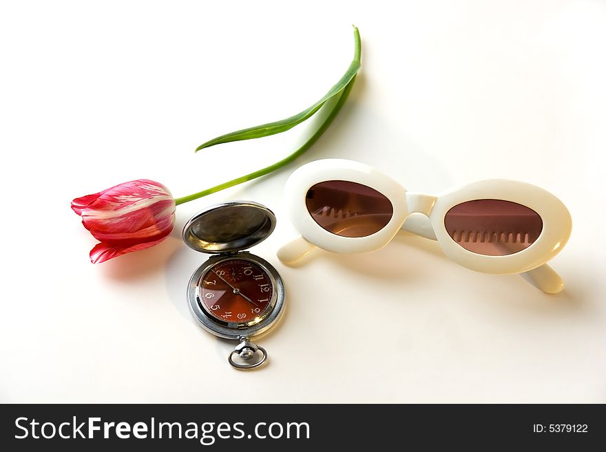 A photo of white old-fashioned sunglasses, red tulip and old watch. A photo of white old-fashioned sunglasses, red tulip and old watch