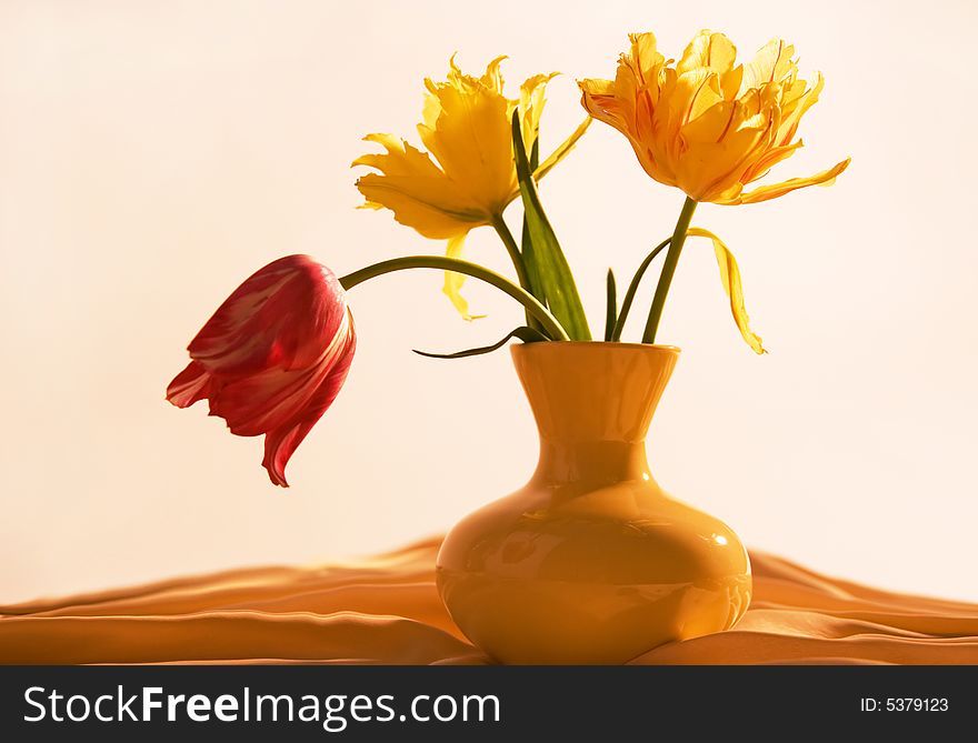 Three tulips in yellow vase on beige background. Three tulips in yellow vase on beige background