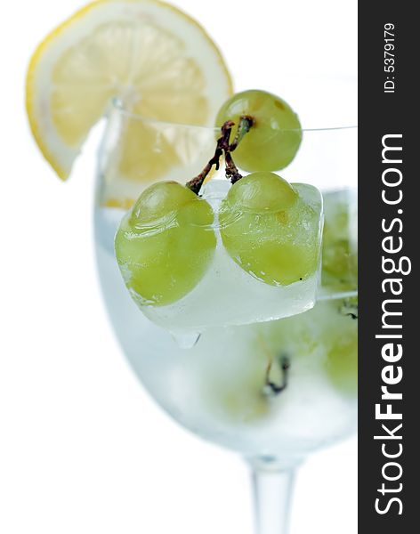 Close up to frozen grapes in wine glass with fresh cut lemon slice. Close up to frozen grapes in wine glass with fresh cut lemon slice