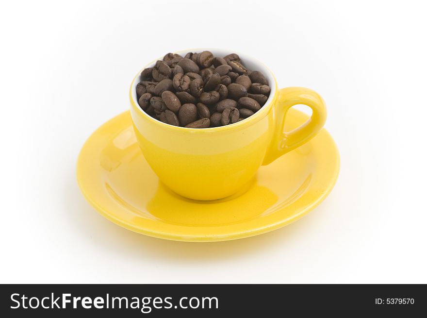 Yellow espresso cup filled with coffee beans