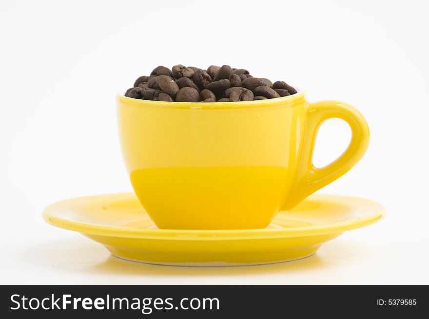 Yellow espresso cup filled with coffee beans