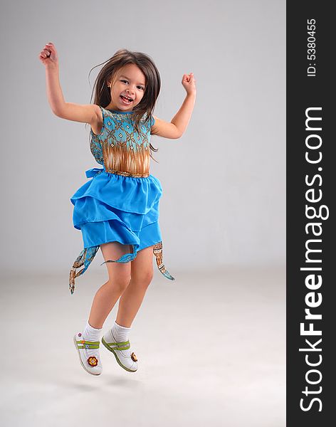 Little cute girl in bright blue dress jumping with excitement. Little cute girl in bright blue dress jumping with excitement