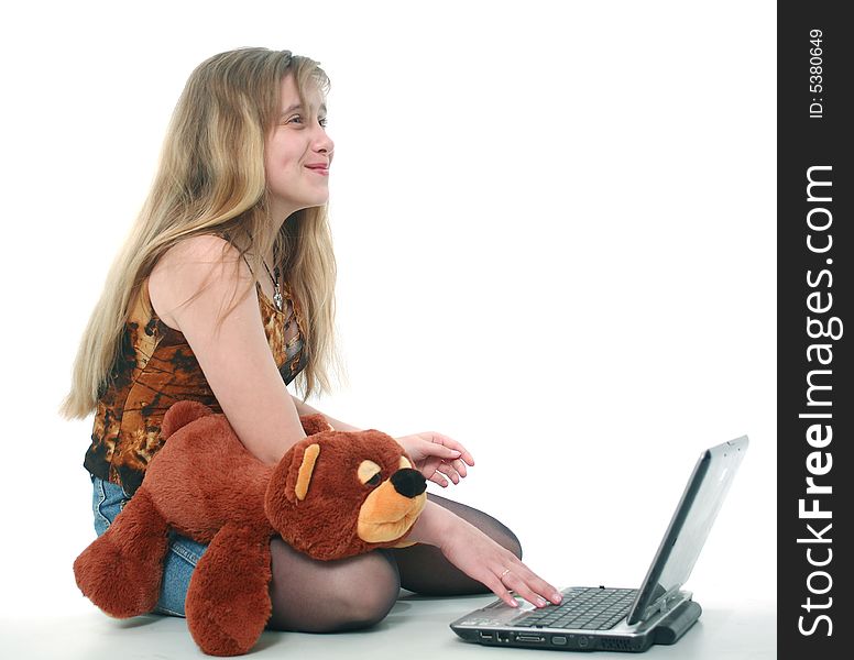 The girl with a toy looks the laptop and smiles. The girl with a toy looks the laptop and smiles
