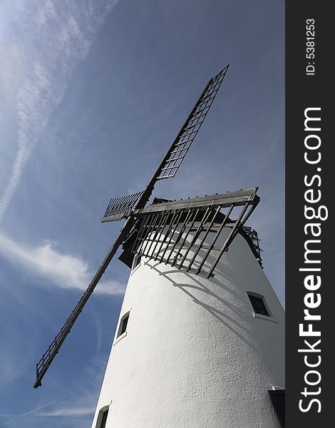 White windmill with black sails against blue sky