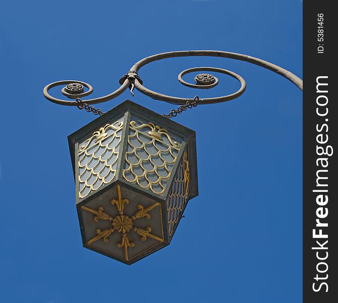 A photo of an old street lamppost against blue sky. A photo of an old street lamppost against blue sky