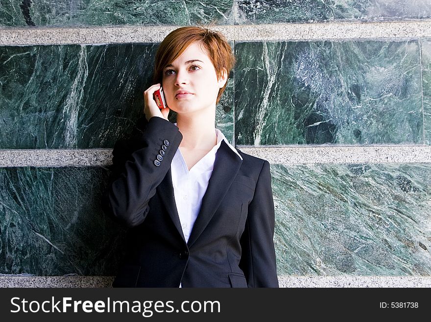 Beautiful businesswoman at phone over marble background.