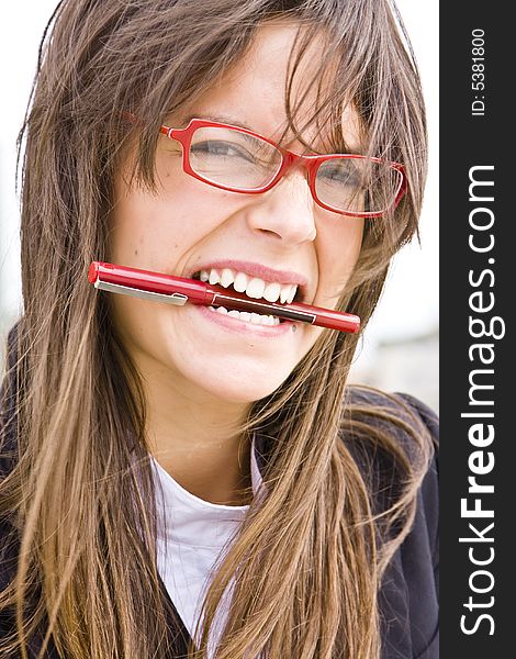 Young businesswoman in red glasses bitin a pen. Young businesswoman in red glasses bitin a pen