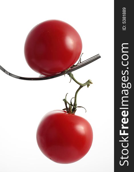 Two tomatoes dangling from a fork