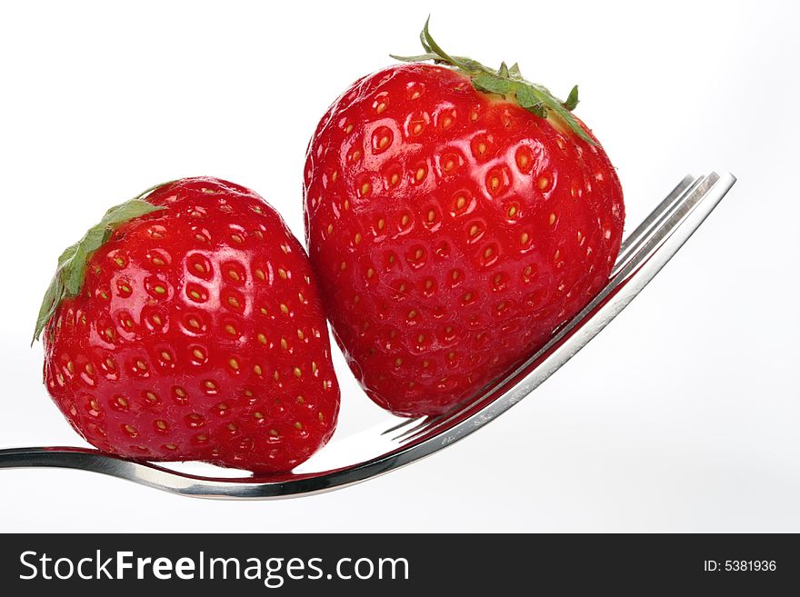 A couple of strawberries on a fork over white background