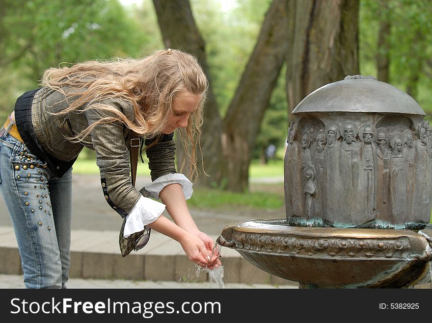 The beautiful girl types water in hands. The beautiful girl types water in hands