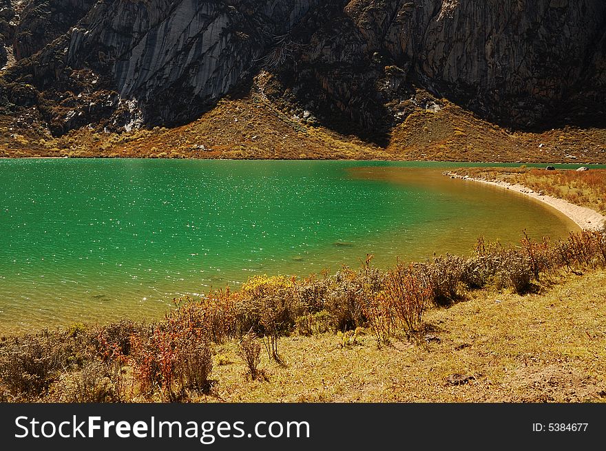 Beautiful green lake water beside mountains on field