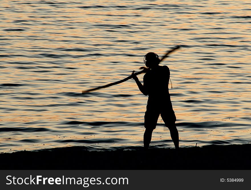 Silhouette of a man practicing martial arts on the beach