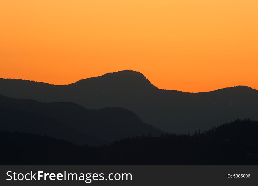 Silhouette of several mountains in the sunset