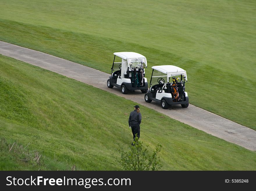 Golf Course Out of Bounds is a capture of someone looking for their ball at the edge of the course with their golf carts parked on the path.