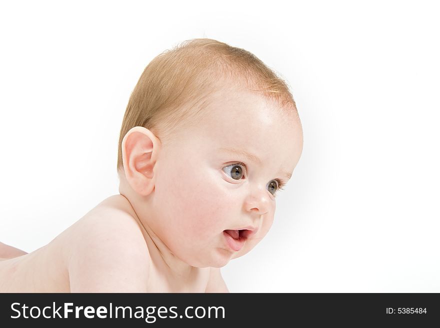 Naked six months old baby lying on his bally isolated on white