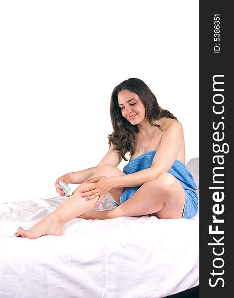 A beautiful girl, sitting on a couch, wrapped in a blue towel, using an epilator on her legs. A beautiful girl, sitting on a couch, wrapped in a blue towel, using an epilator on her legs