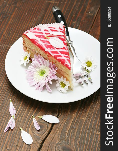 A slice of a cream cake and flowers.