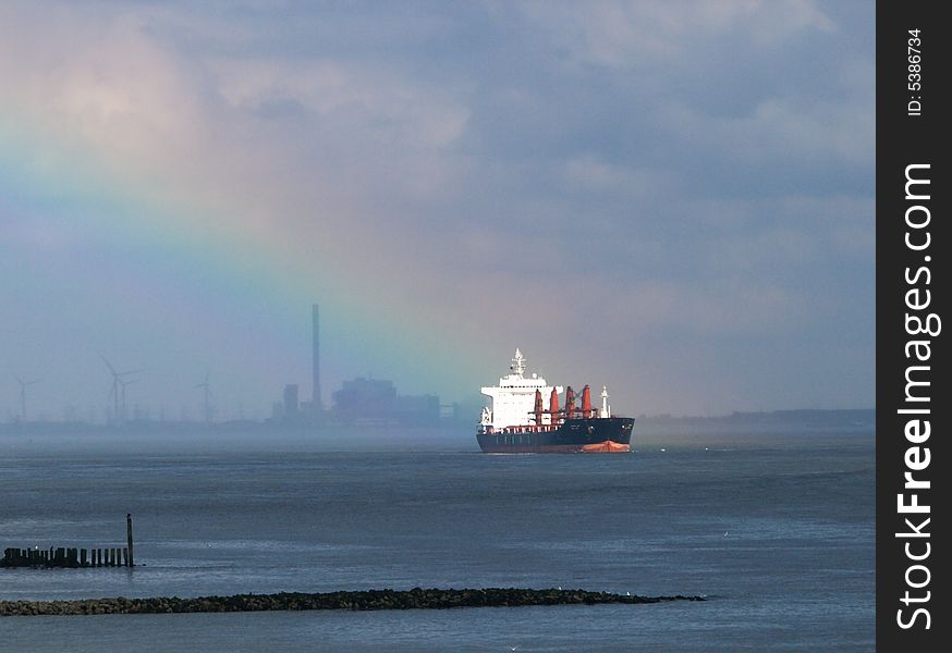 A freight boat lighted up by a rainbow. A freight boat lighted up by a rainbow