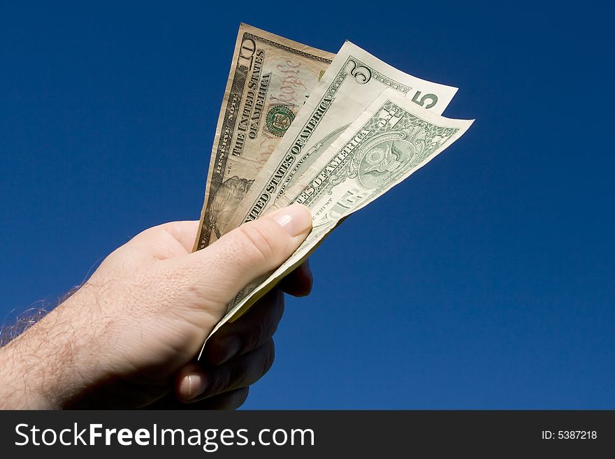 Various dollar bills held in a hand on blue background. Various dollar bills held in a hand on blue background