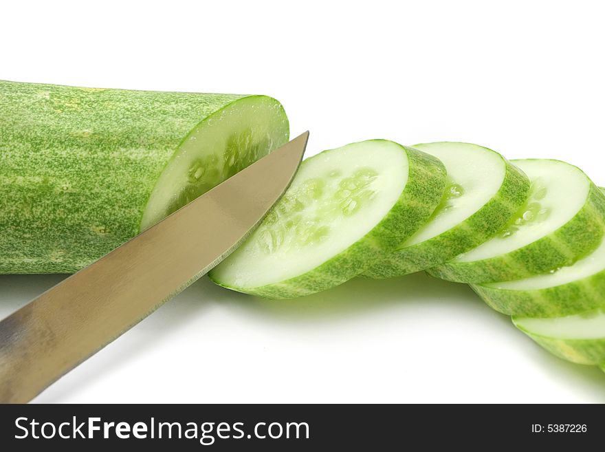 Cucumber slices with small knife on white background.