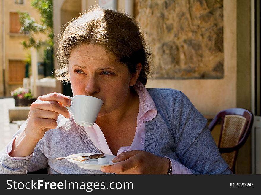Young woman drinking a cup of coffee at a terrace. Young woman drinking a cup of coffee at a terrace