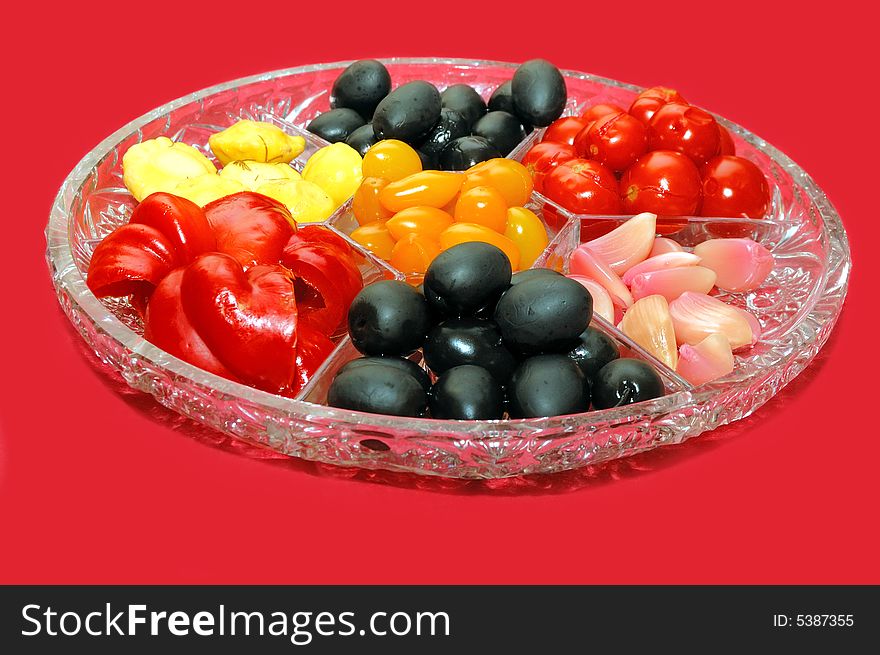 Tomato, olives and sweet pepper on the plate over a red background