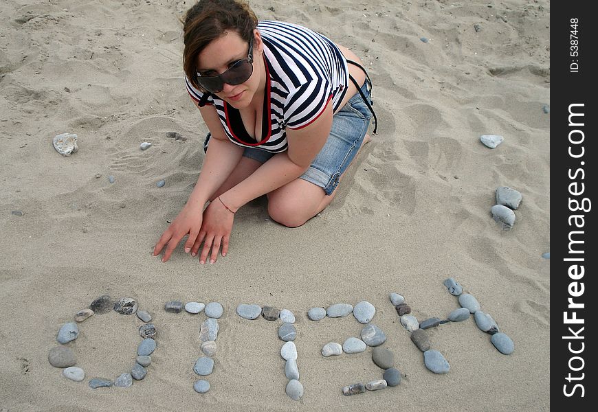 A girl writes hello with stones on the beach. A girl writes hello with stones on the beach