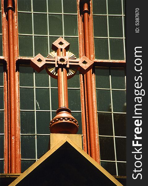 Detail of church cross in front of window. Detail of church cross in front of window