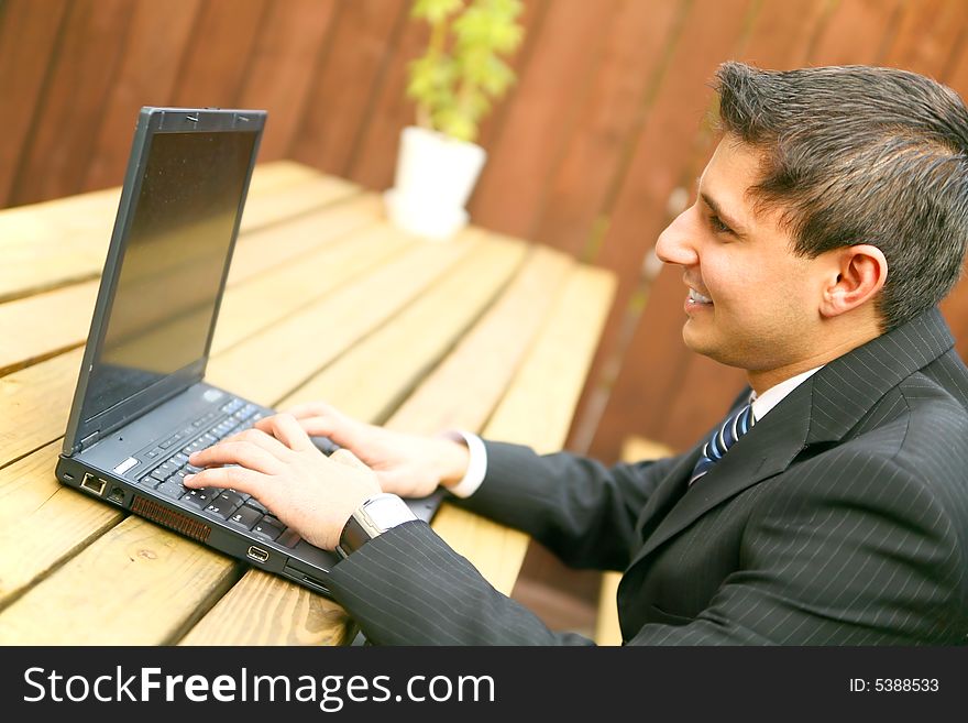 Businessman smiling while working on his laptop outdoor. Businessman smiling while working on his laptop outdoor