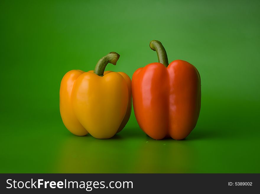 Yellow and orange paprika on the green background