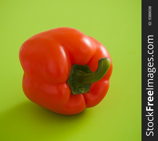 Single orange pepper over the green background