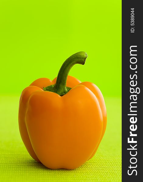 Single orange pepper over the green background