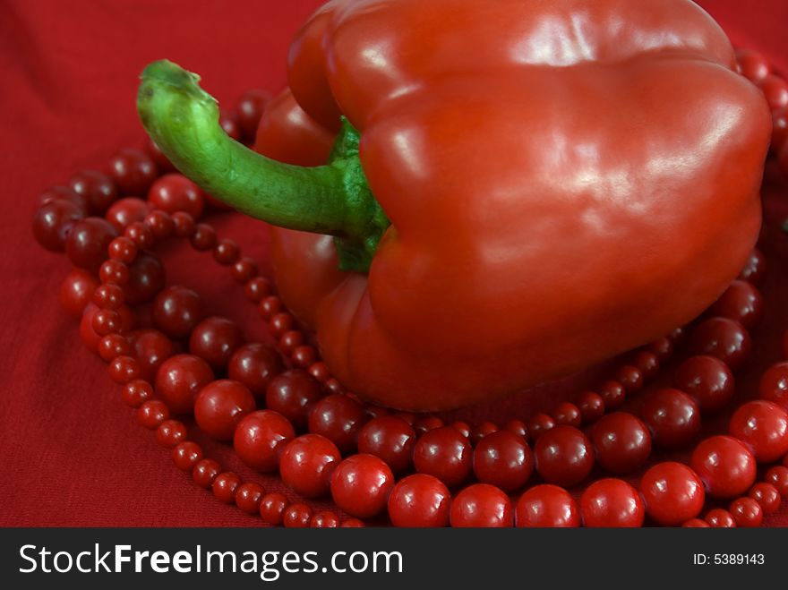 Red paprika and red beads on the red background. Red paprika and red beads on the red background