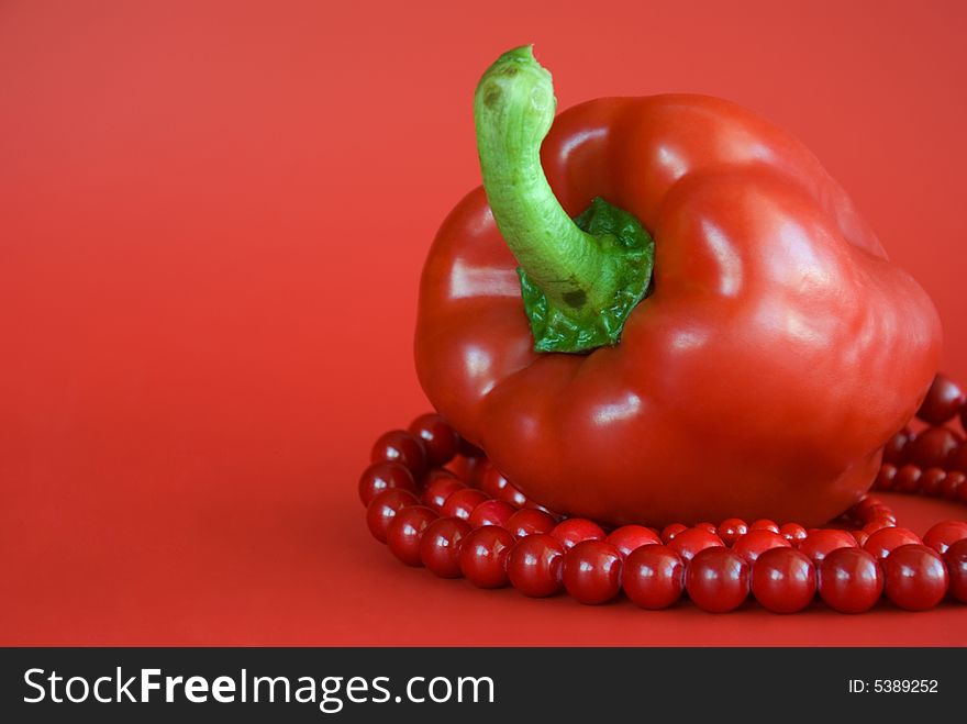 Red paprika and red beads on the red background. Red paprika and red beads on the red background