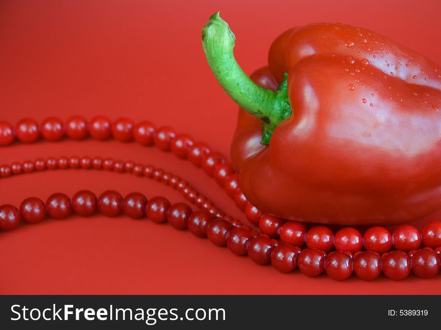 Red paprika and red beads with drops of water