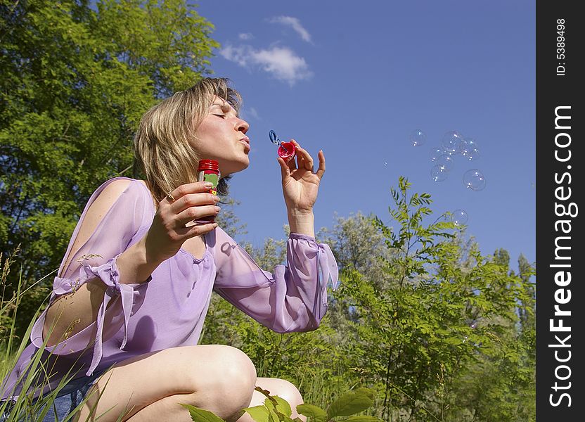 Cute young woman blows a soap bubbles