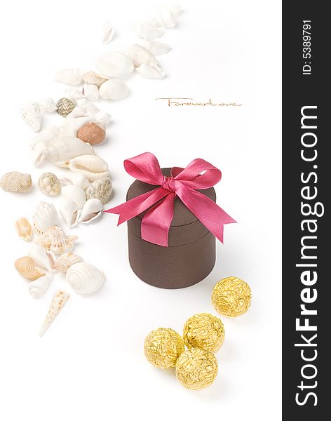 Holiday gift with red riband and various seashells on the white background.