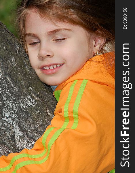 Little girl with a happy smile on her face hugging a tree. Little girl with a happy smile on her face hugging a tree